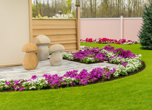 Drei handgefertigte Steinpilze auf einer blumenumrankten Terrasse dekorativ arrangiert.