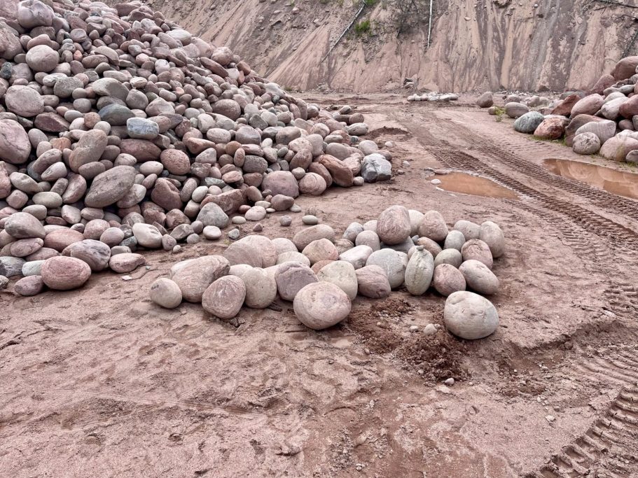 Findlinge vor Ort in Lappland Mehrere große, glatte Steine sind auf einem Kiesboden angeordnet, umgeben von Schotter.