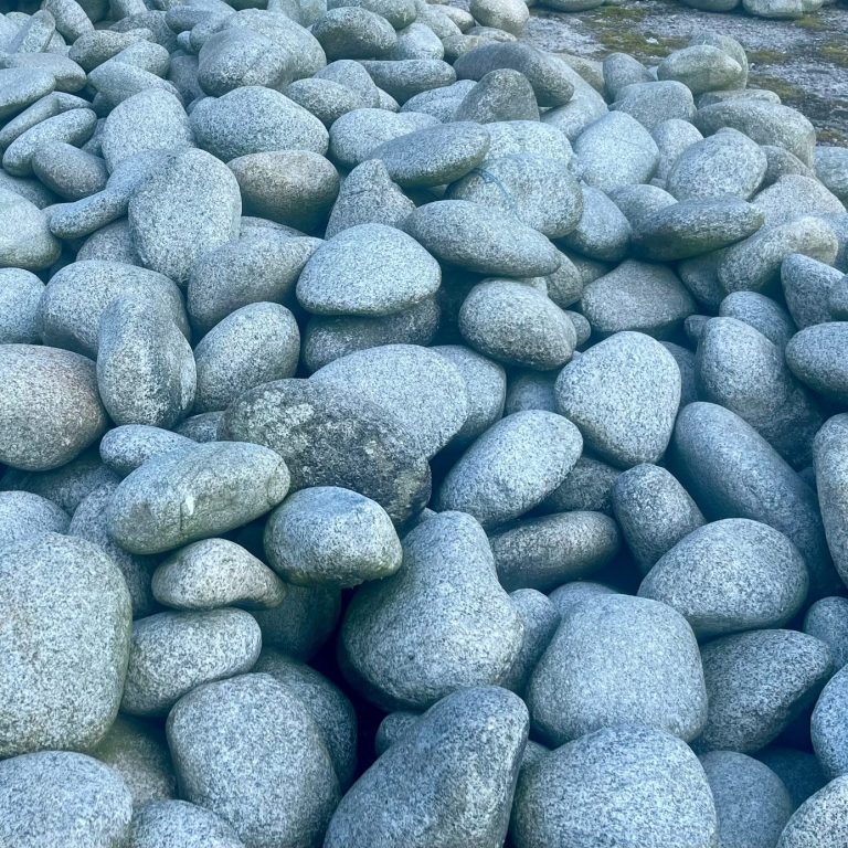 Findlinge für Urnengräber Grau-weiße Findlinge liegen übereinander, unregelmäßig angeordnet.