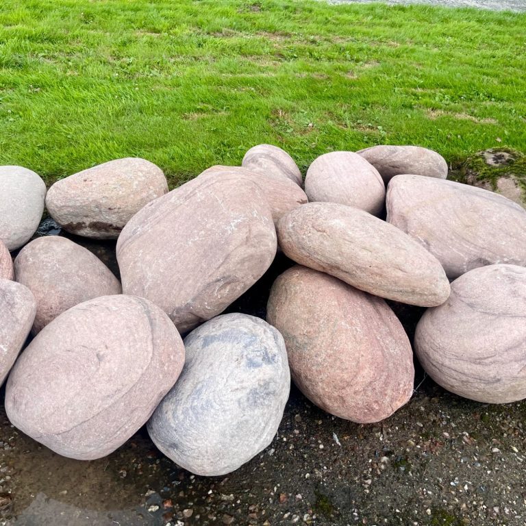 Flache, runde Steine in verschiedenen Grautönen auf grünem Gras.
