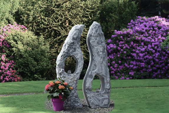Twinrocks-Springbrunnen aus Marmor, sanft beleuchtet – eingebettet in einen weitläufigen, parkähnlichen Garten