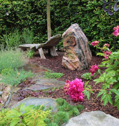 Ein Platz zum Verweilen – der skandinavische Findling fügt sich wie selbstverständlich in die stille Gartenidylle.